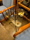 A 1950s French black lacquer and brass tripod floor lamp with glass centre table