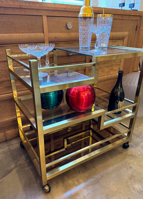 A 1970s Romeo Rega Italian bar trolley with multiple smoked glass shelves