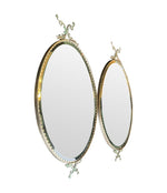 A pair of Italian 1940s oval mirrors with dolphin detailing around the brass frame