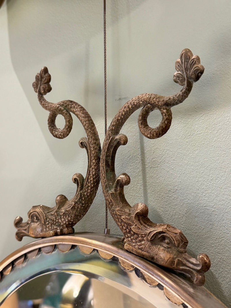 A pair of Italian 1940s oval mirrors with dolphin detailing around the brass frame